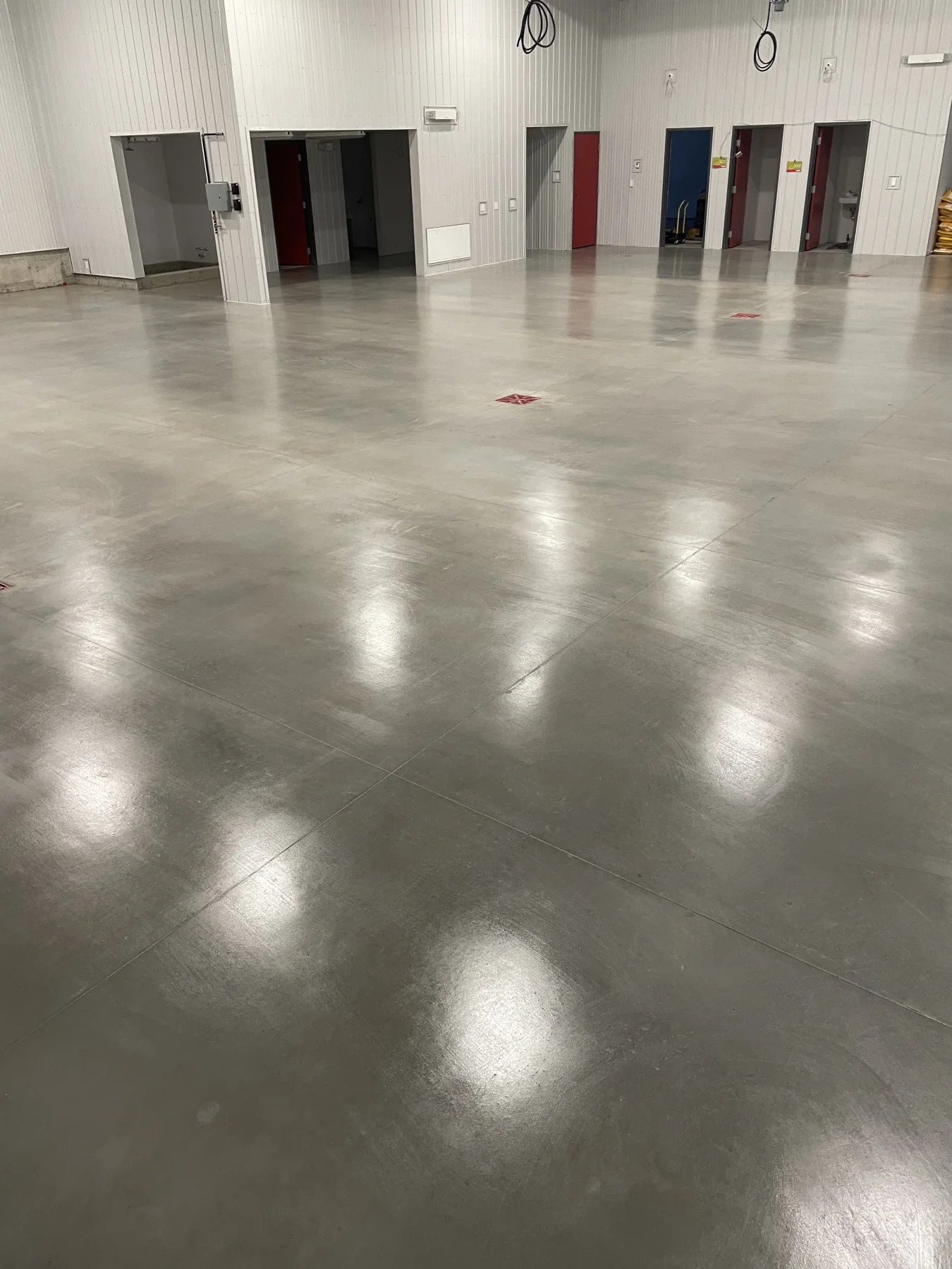 Finished sealed concrete floor with visible reflections and control joints in an industrial facility