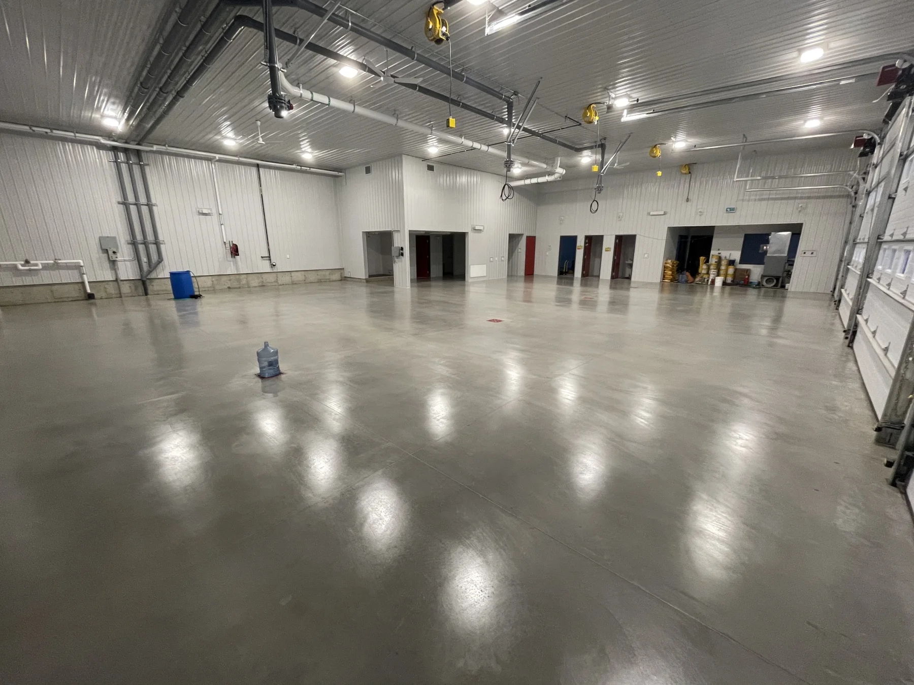 Wide view of a finished sealed concrete floor reflecting overhead lights in an industrial shop