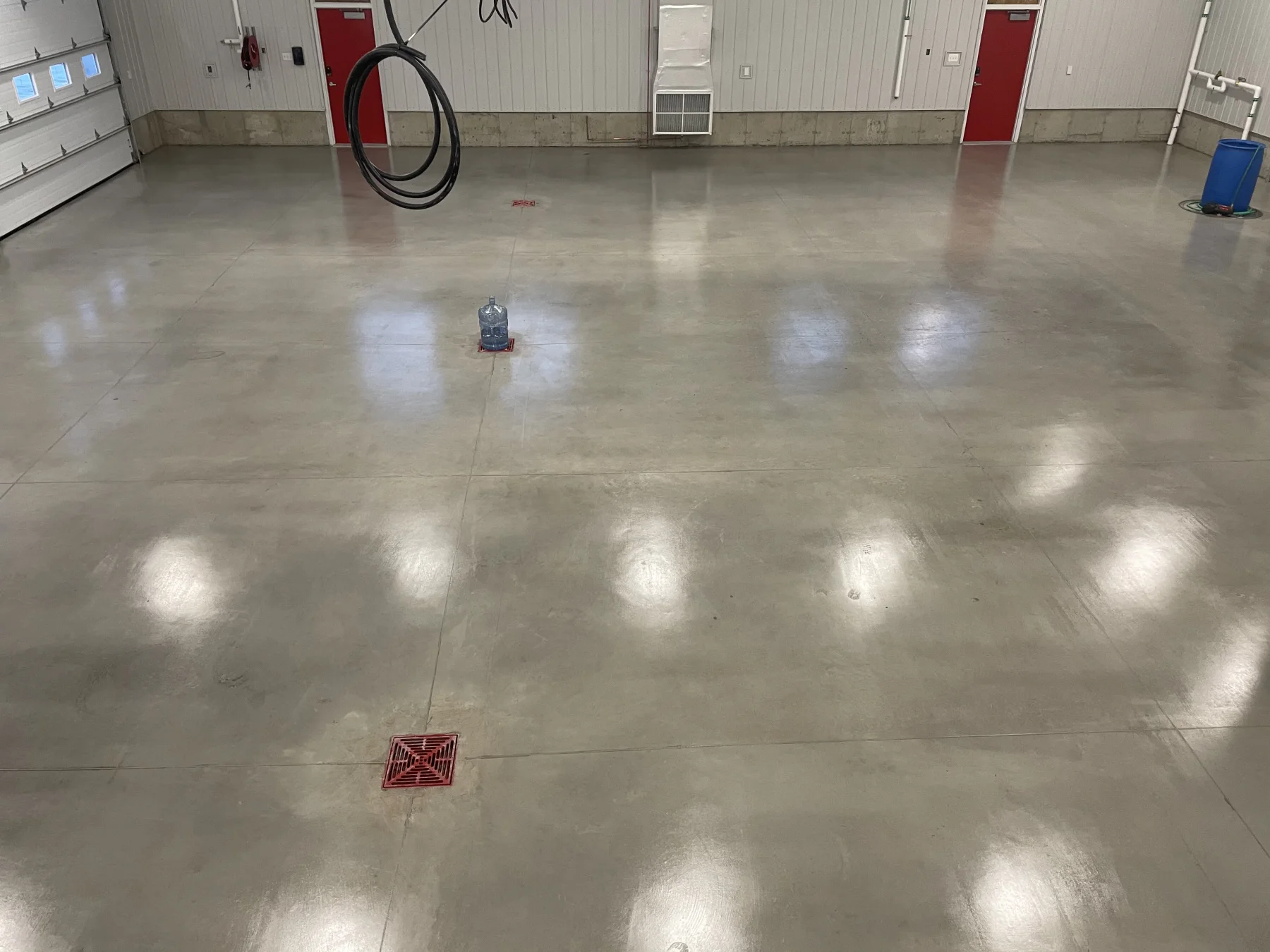 Finished sealed concrete floor surrounding red drainage grates in an industrial shop