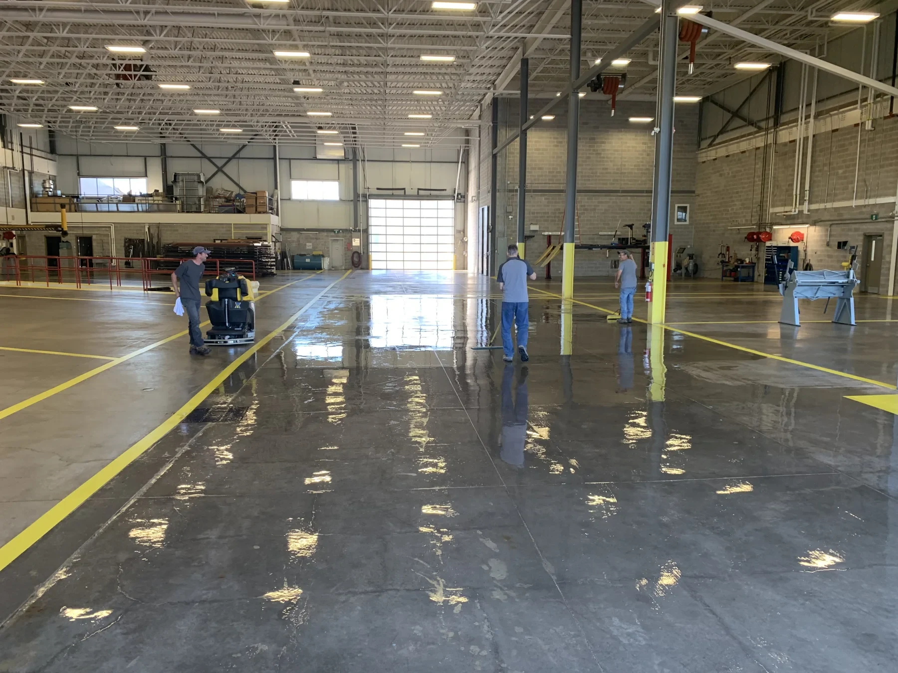 Crew applying concrete sealer across a large industrial service floor