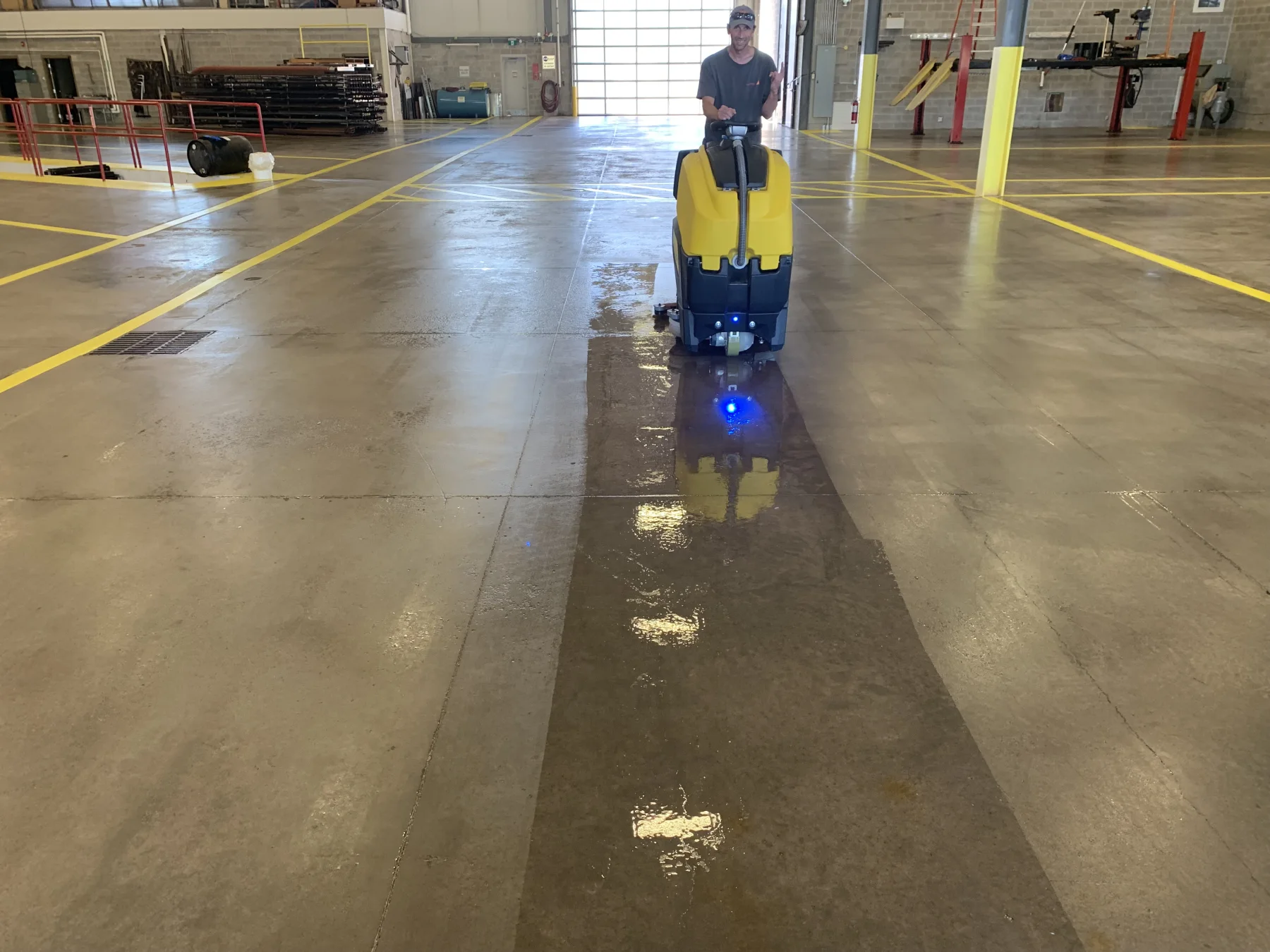 Floor scrubber cleaning a sealed concrete floor in a large industrial service shop