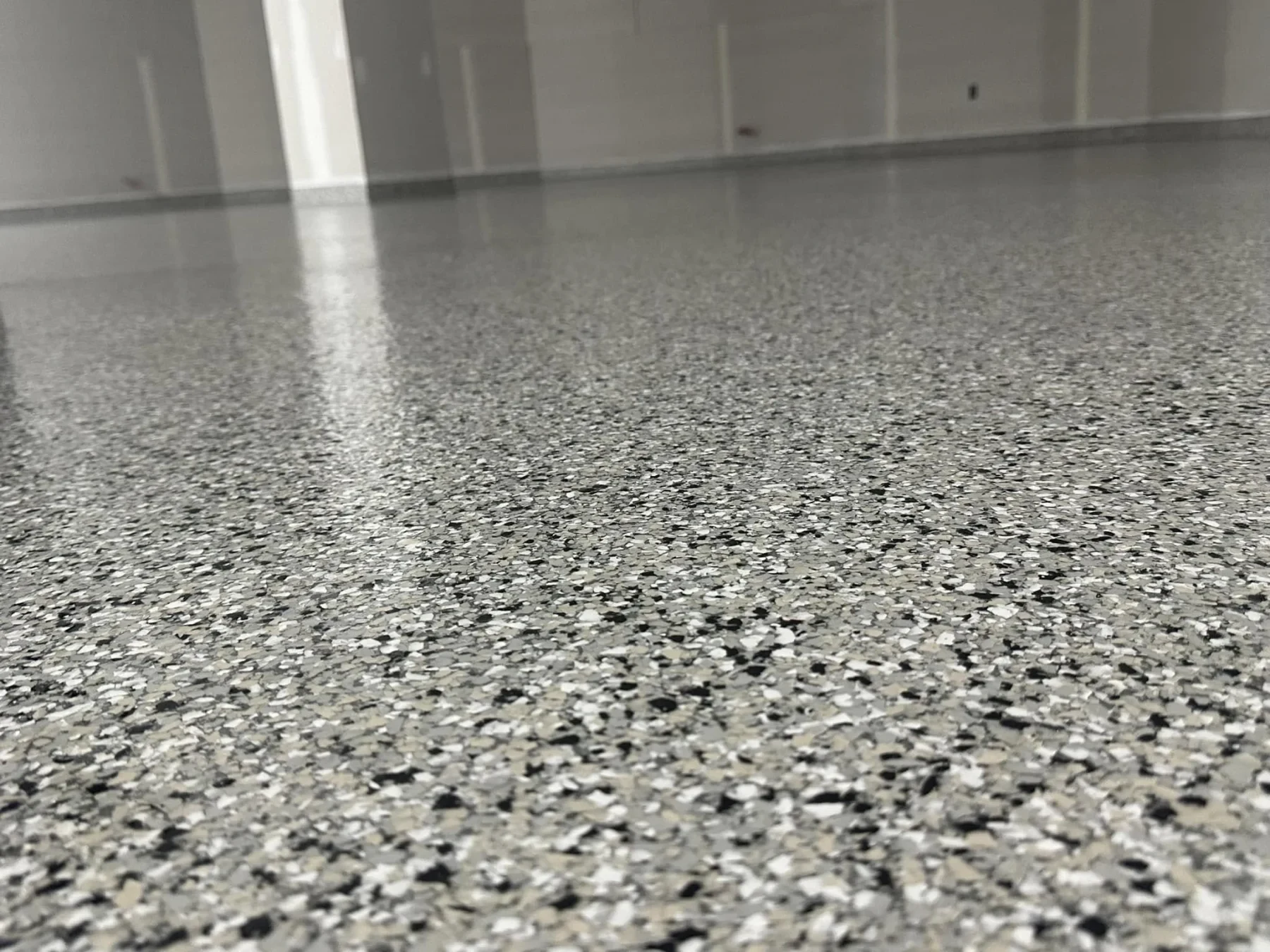 Close-up view of a glossy grey, white and black decorative flake floor