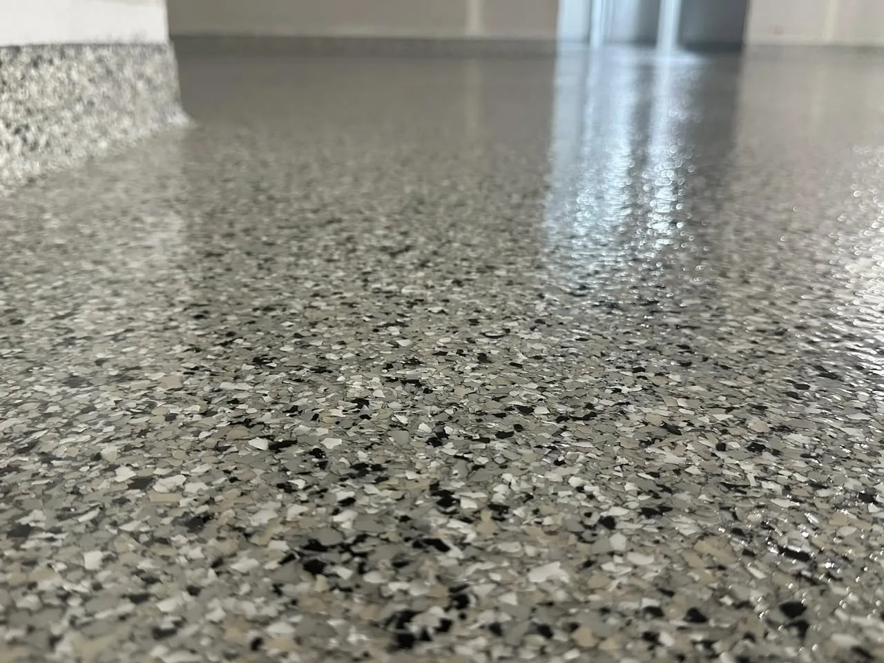 Close-up of grey decorative flake flooring beside an integral cove base
