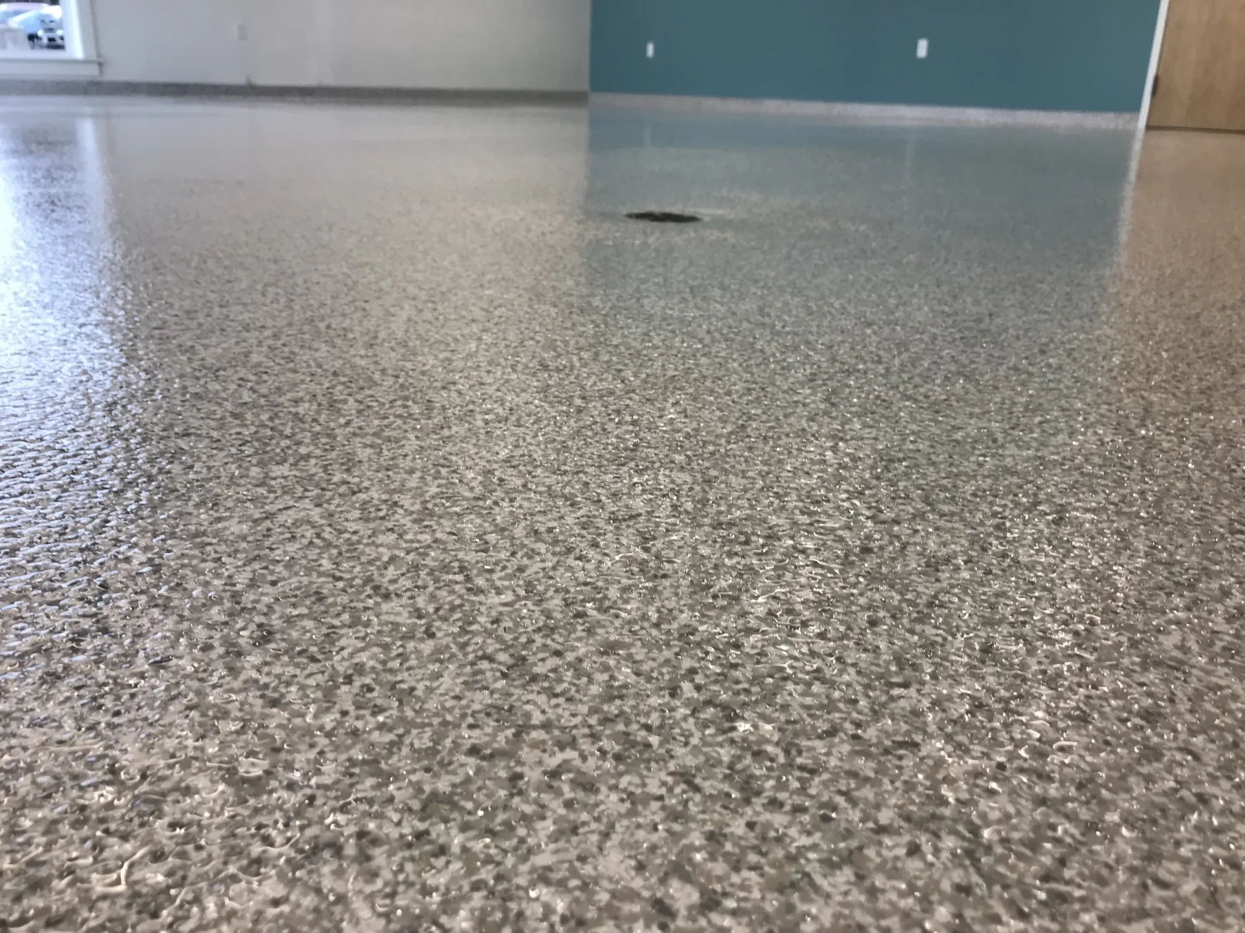 Low-angle view of grey decorative flake flooring surrounding a floor drain
