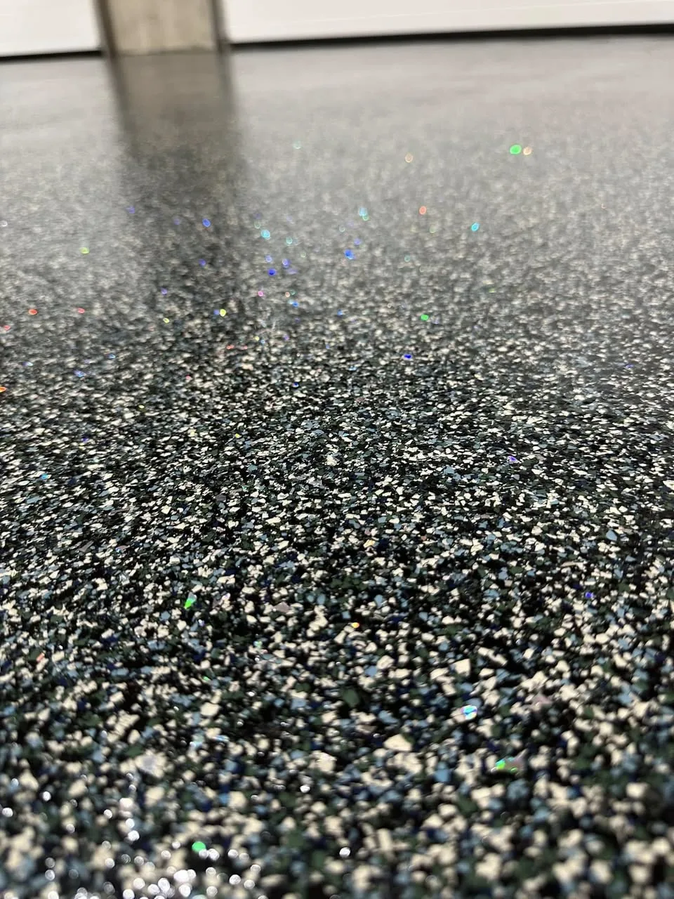 Close-up of a dark decorative flake floor with reflective accent chips