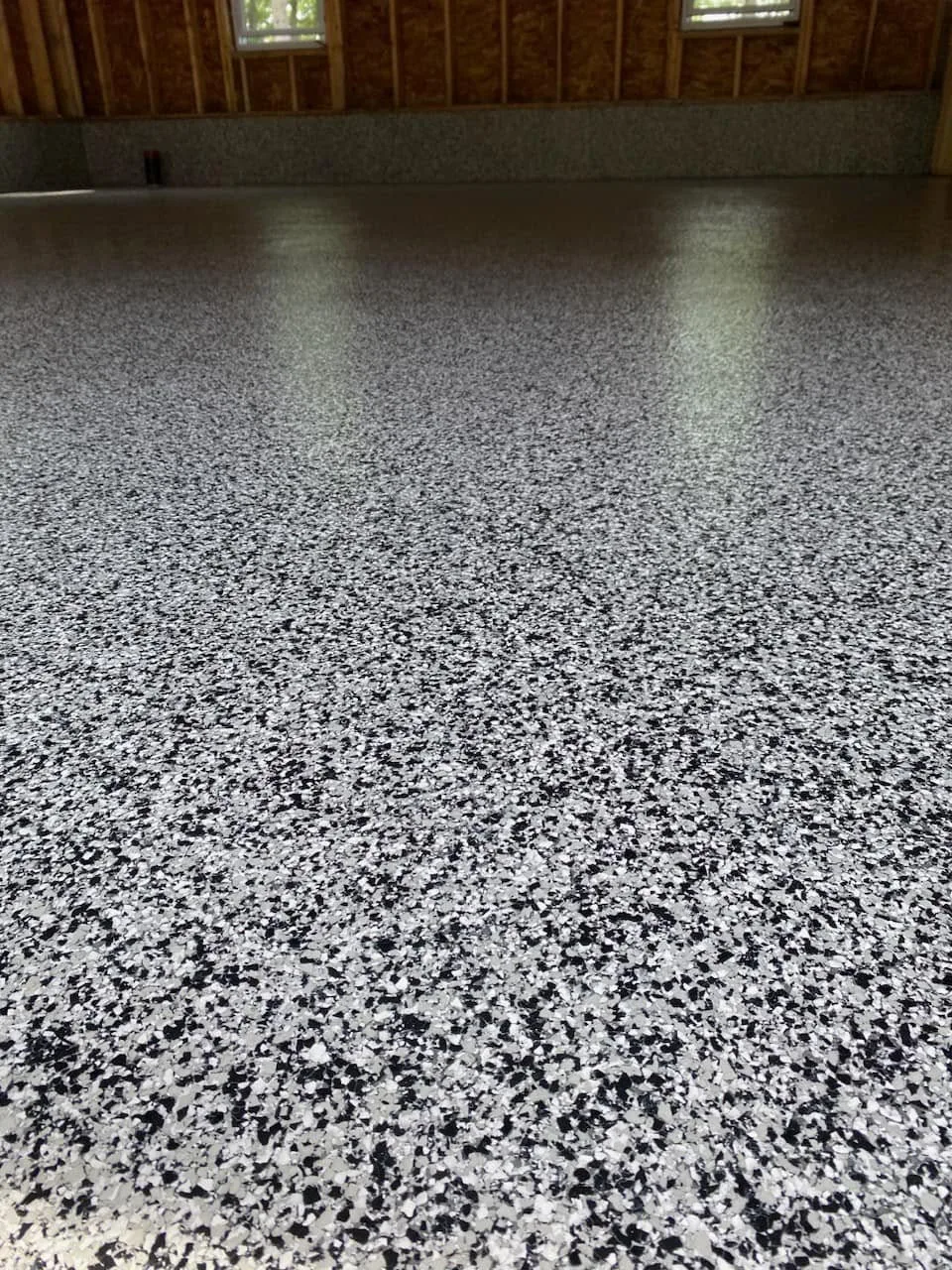 Grey and black decorative flake flooring installed in a garage under construction