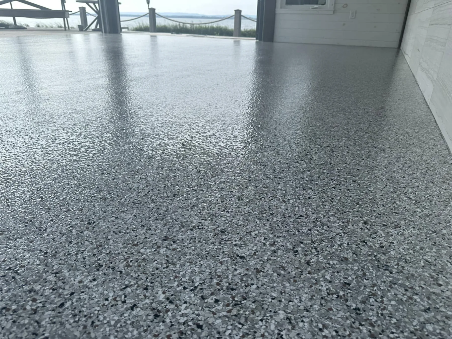 Grey decorative flake flooring in a waterfront garage with an open view