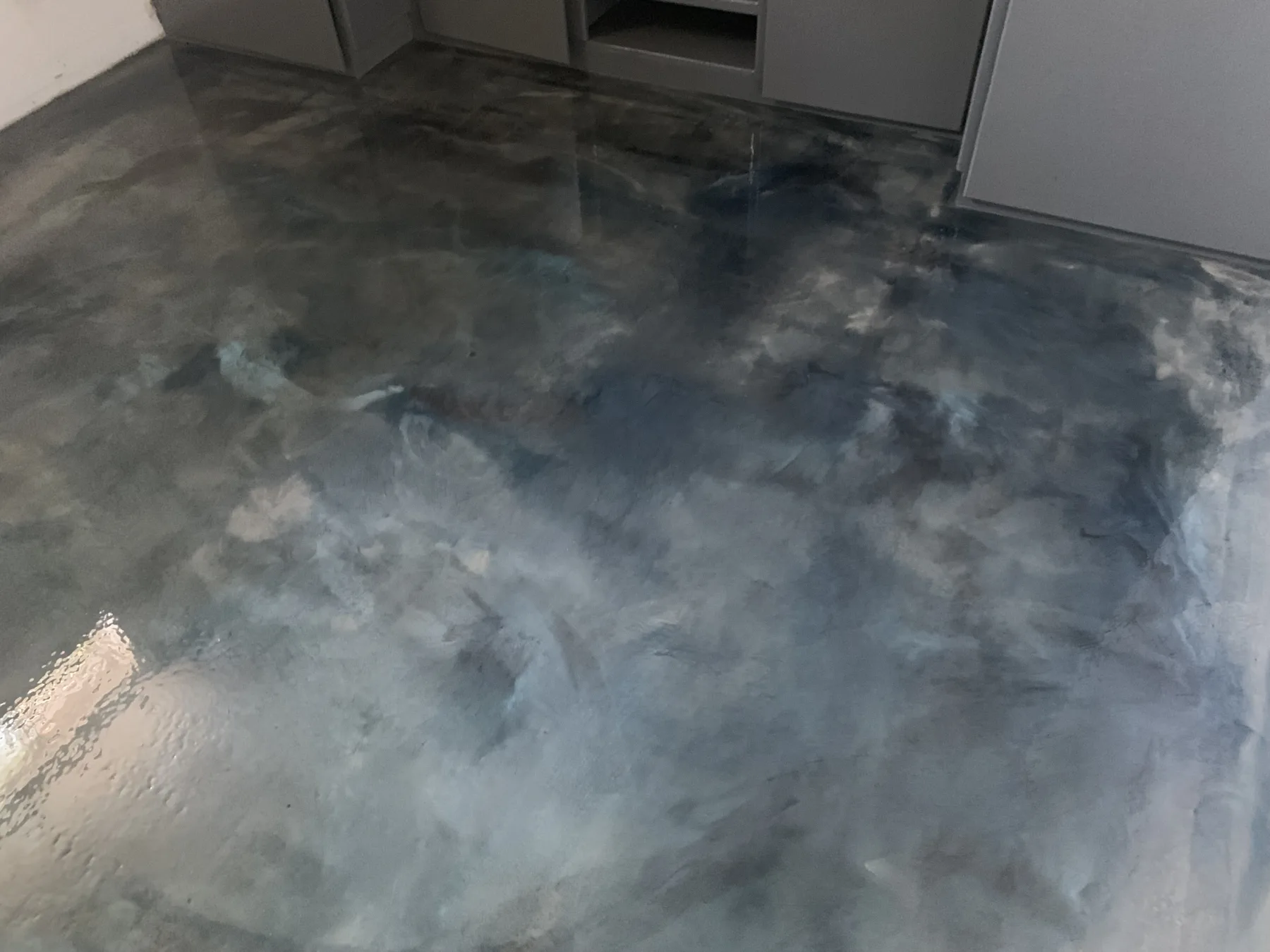 Close view of a glossy blue-grey metallic floor with layered cloud-like movement
