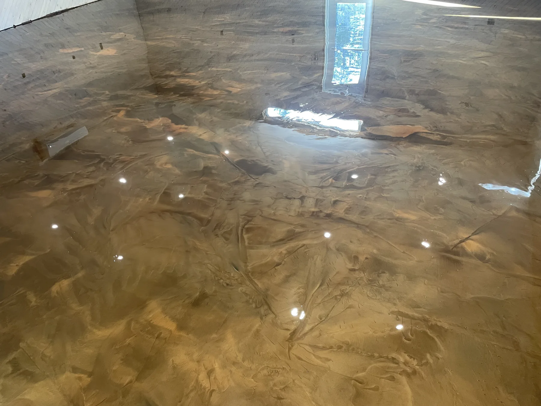 Reflective gold metallic floor showing layered hand-applied movement and dark accents