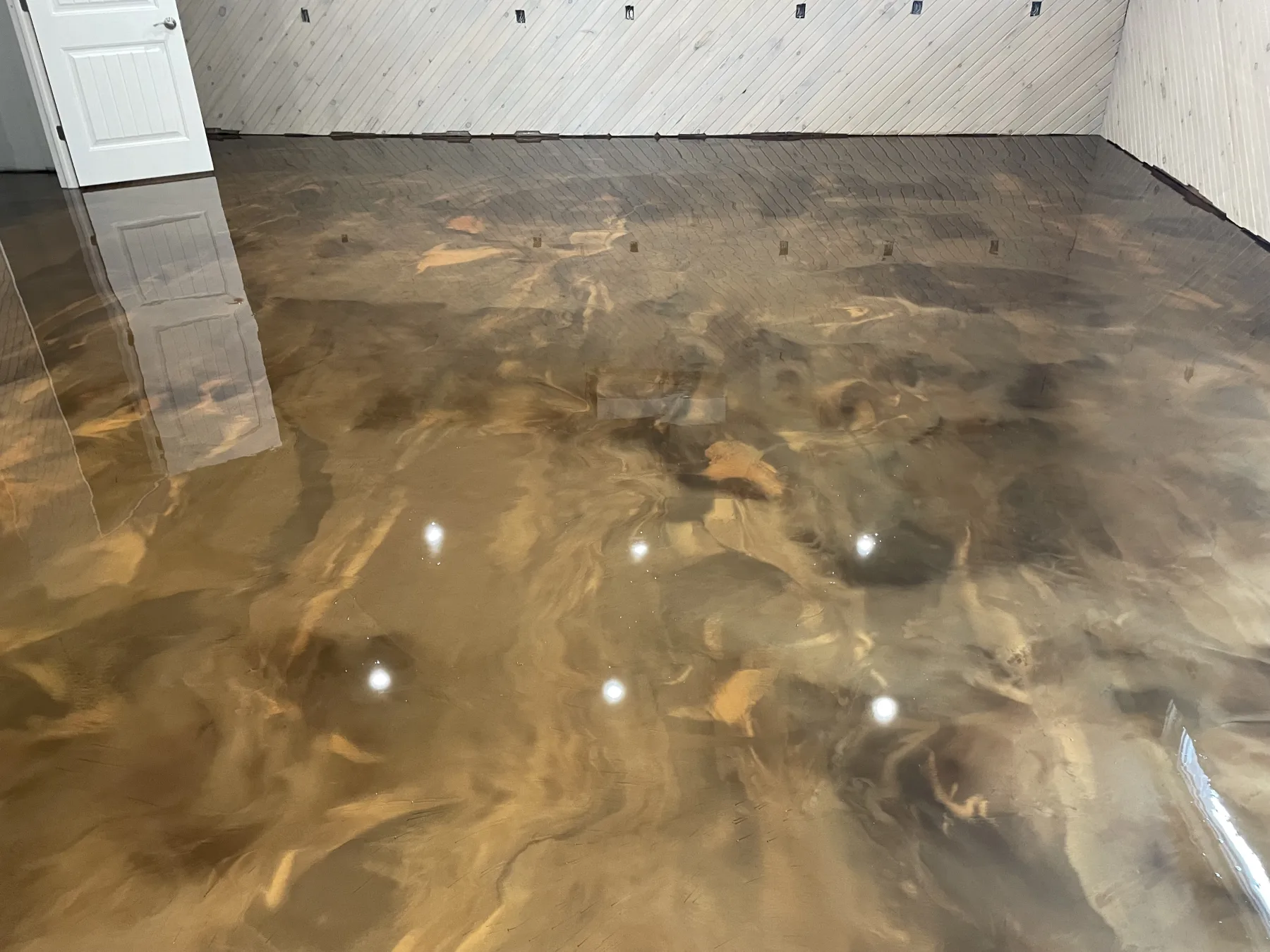 High-gloss gold and bronze metallic flooring with flowing tonal movement across a finished room