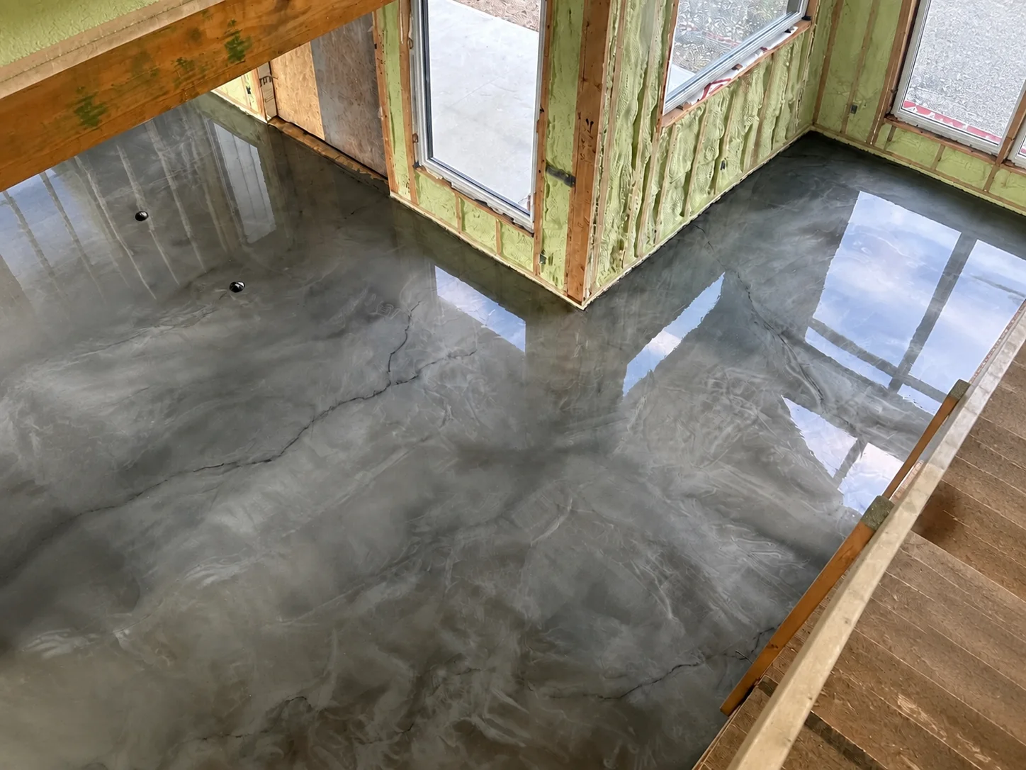 Glossy silver-grey metallic flooring installed throughout a room under construction