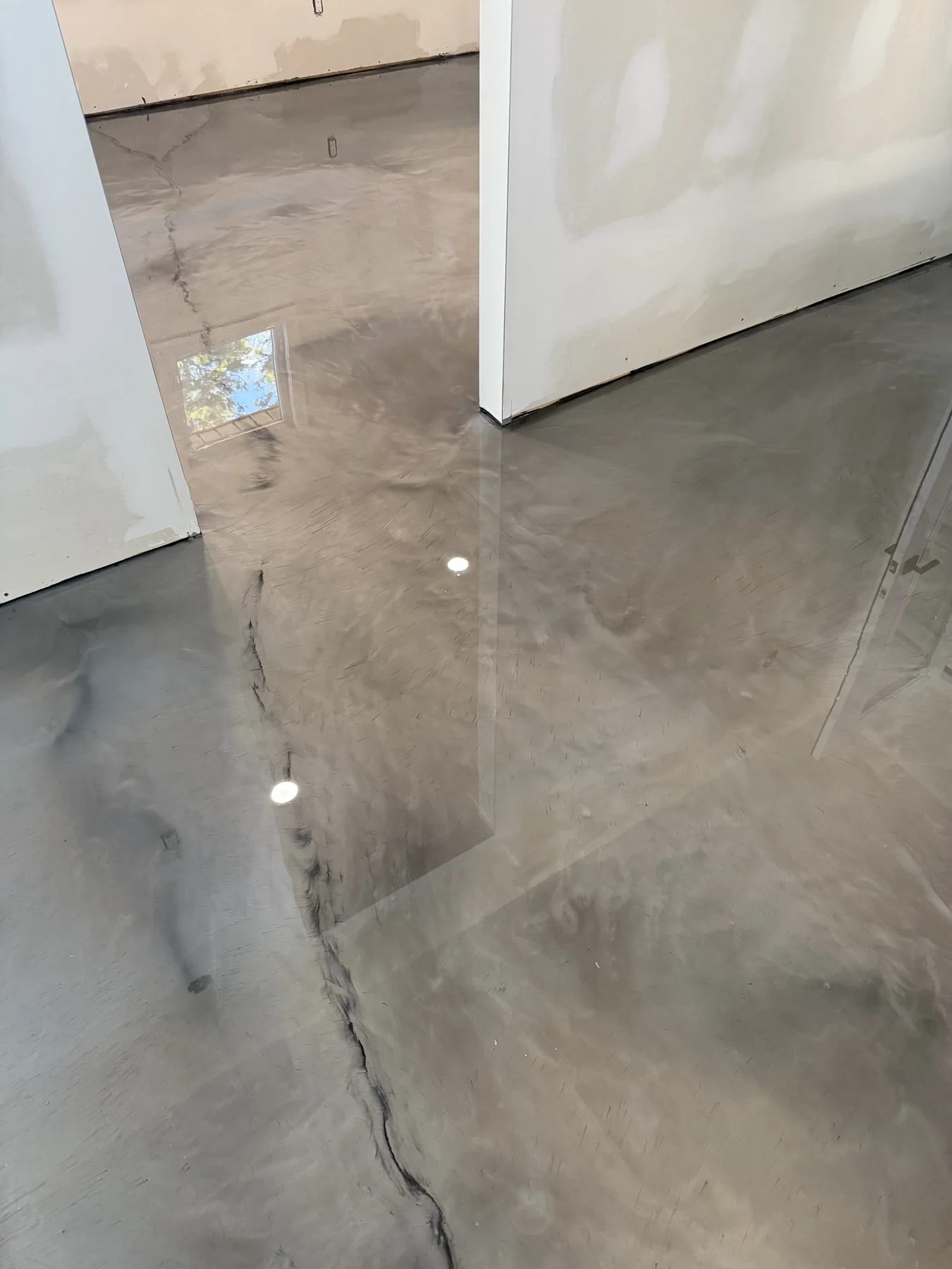 Reflective silver-grey metallic flooring extending between rooms in an interior under construction