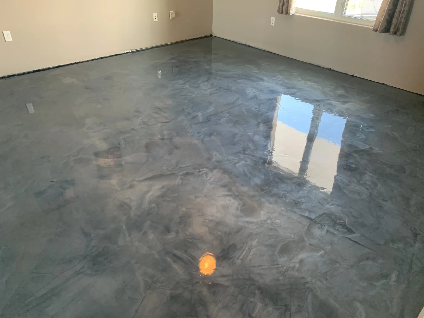 Reflective silver-grey metallic floor with flowing tonal movement in a finished room