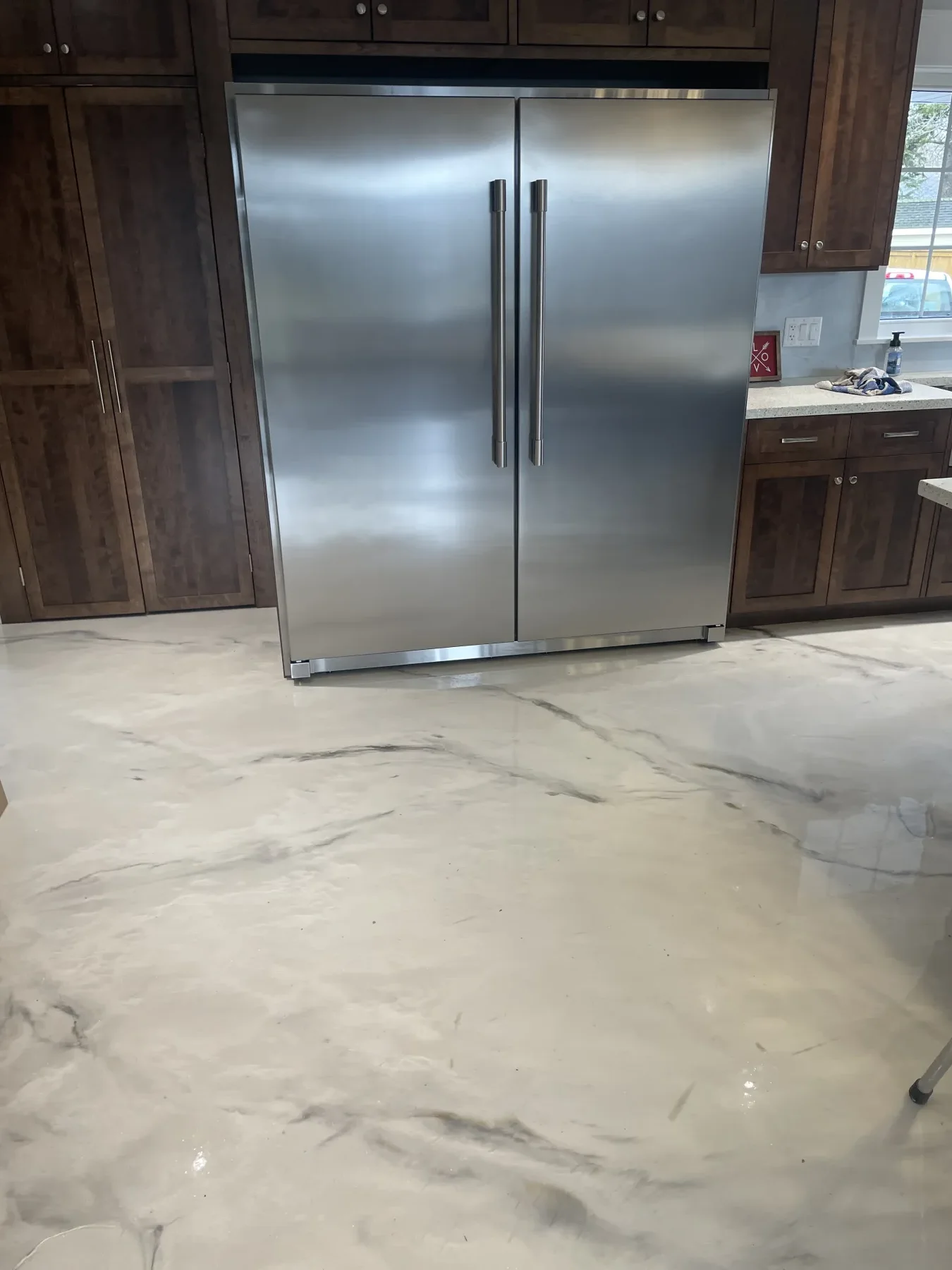 Glossy white and grey marble-style metallic flooring surrounding kitchen cabinetry