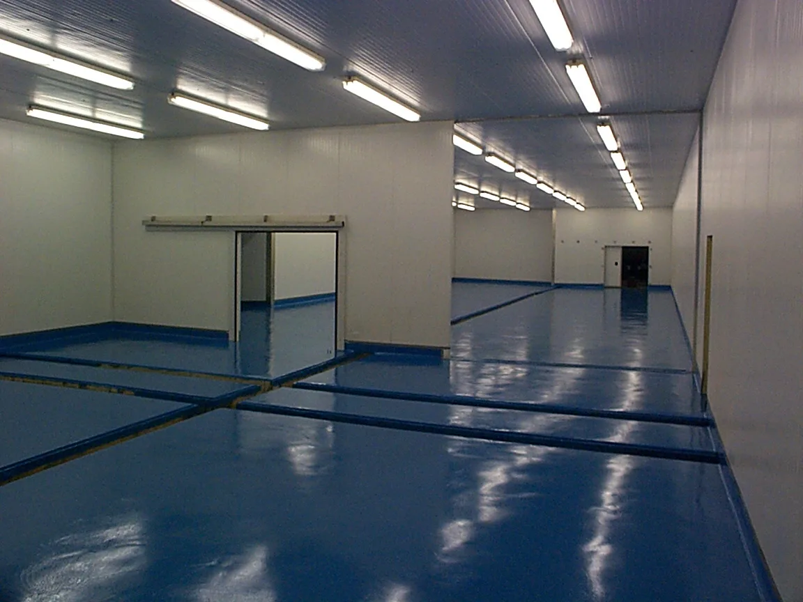 Glossy blue seamless epoxy floor with matching cove bases in a large industrial room