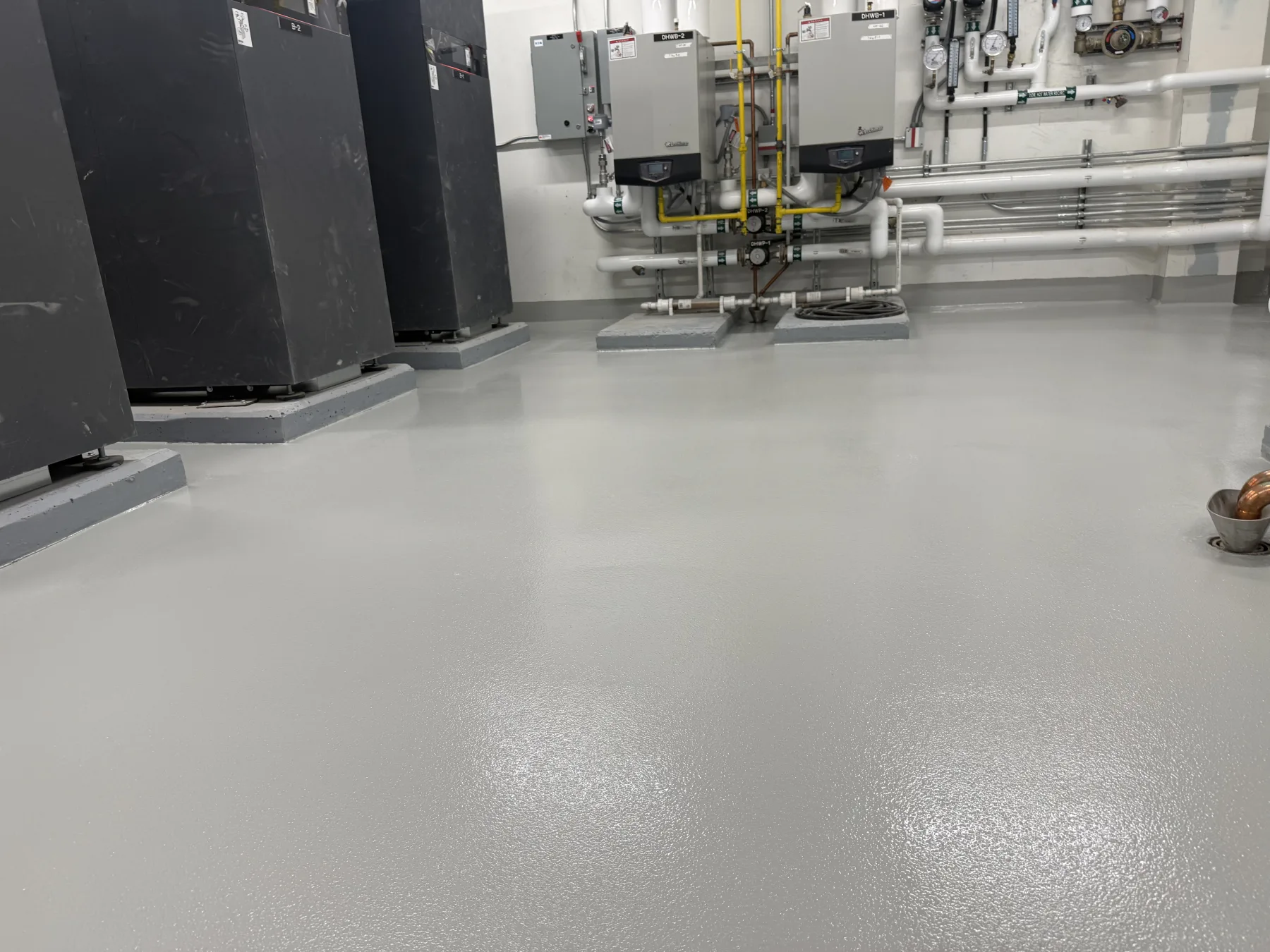 Light-grey seamless epoxy floor installed around boilers, piping and equipment pads