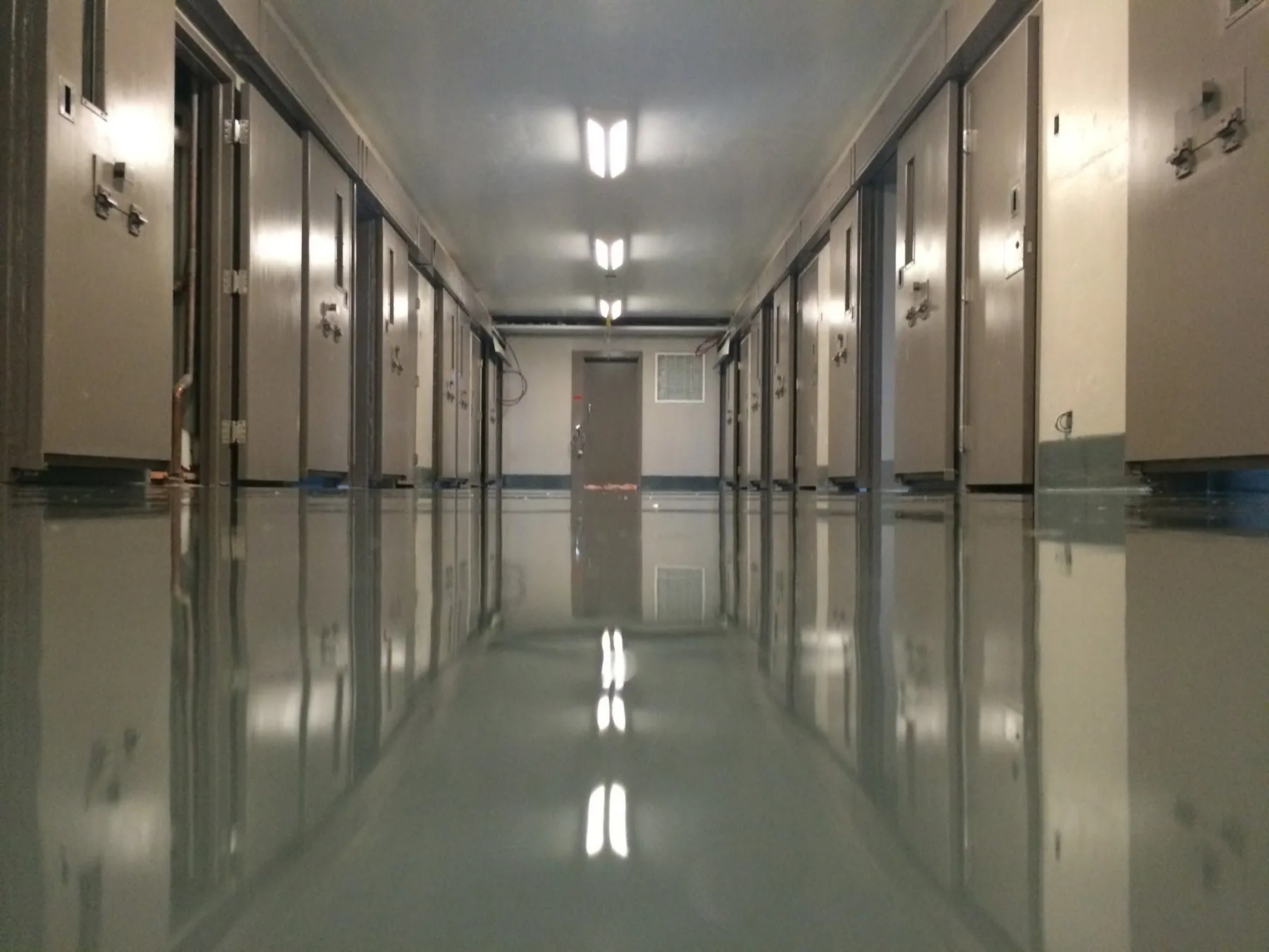 Glossy seamless floor extending through a cold-storage or institutional corridor