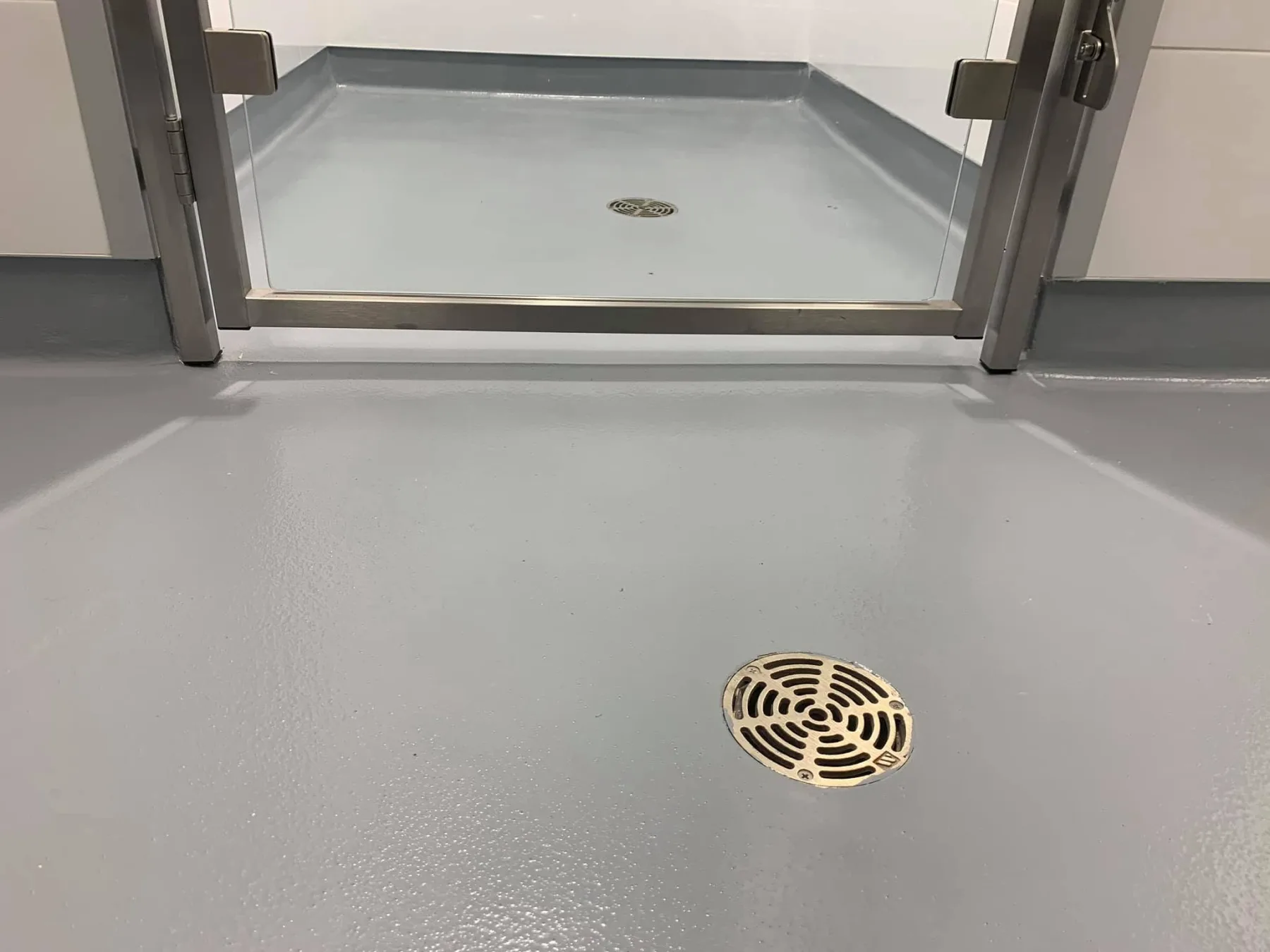 Light-grey seamless floor with integral cove bases and two carefully finished drains
