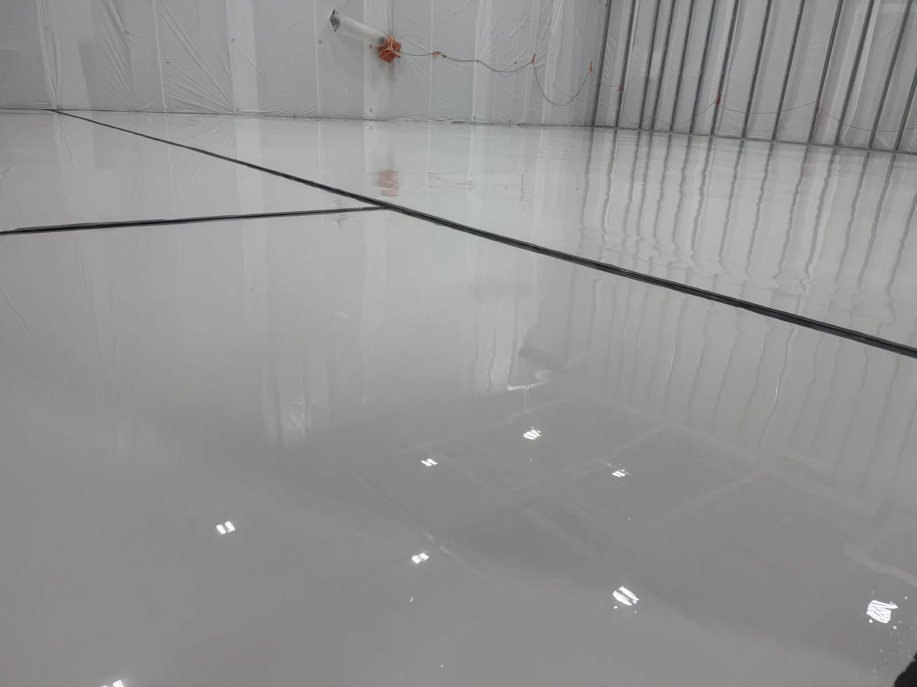 Light-grey seamless epoxy floor with neatly detailed expansion joints in a large building