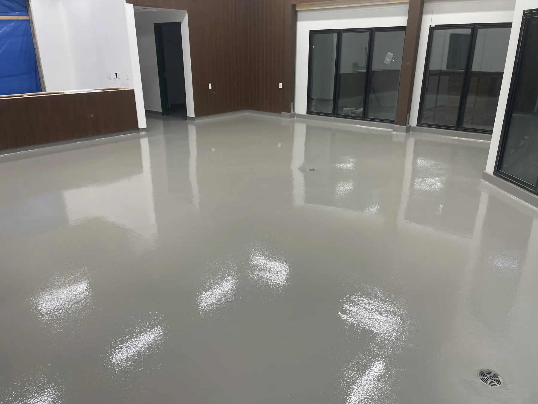 Glossy seamless grey epoxy floor in a finished commercial interior with large windows