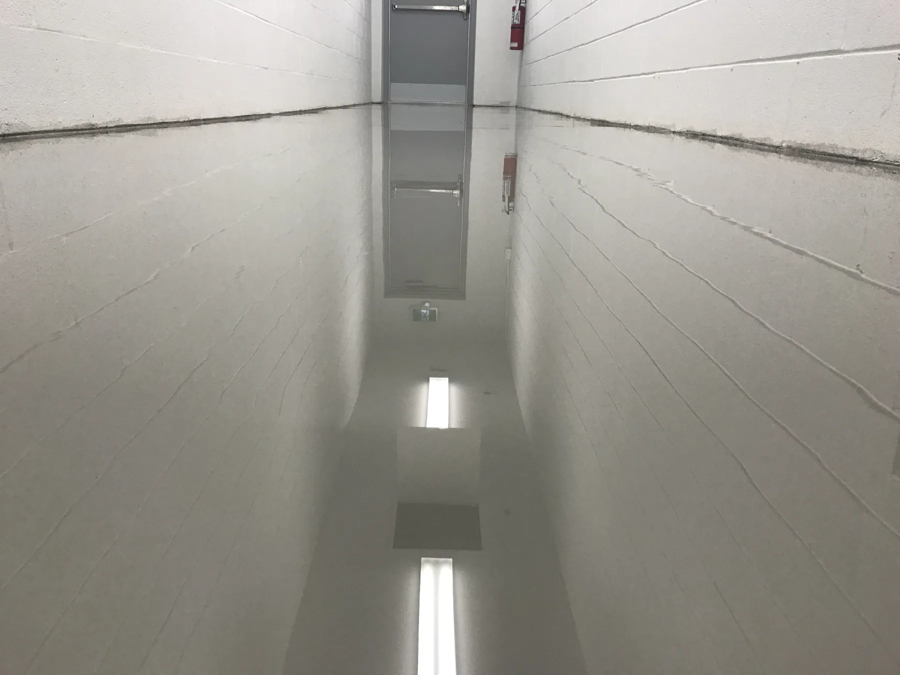 Highly reflective grey seamless epoxy flooring in a narrow service corridor