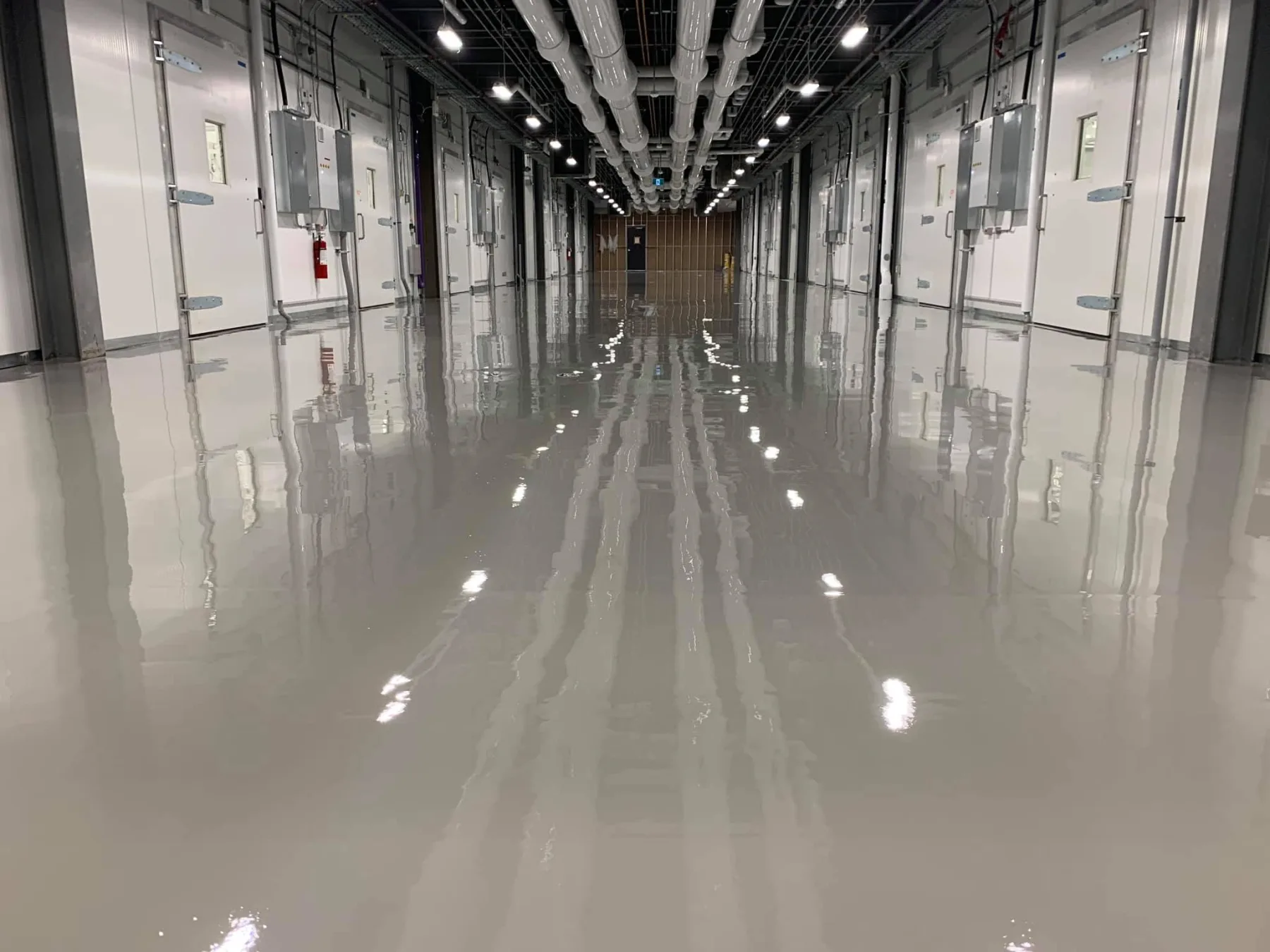 Highly reflective seamless grey epoxy flooring throughout a large industrial corridor