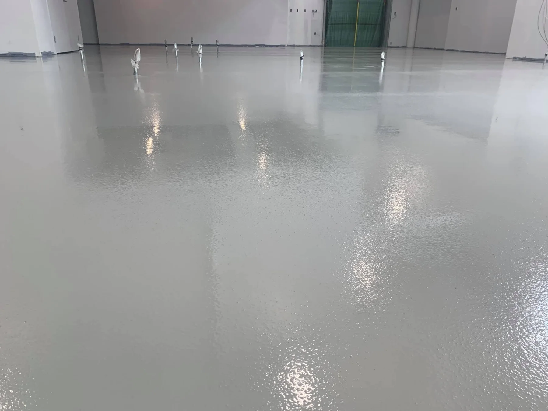 Expansive light-grey seamless epoxy floor in a large unfinished commercial interior