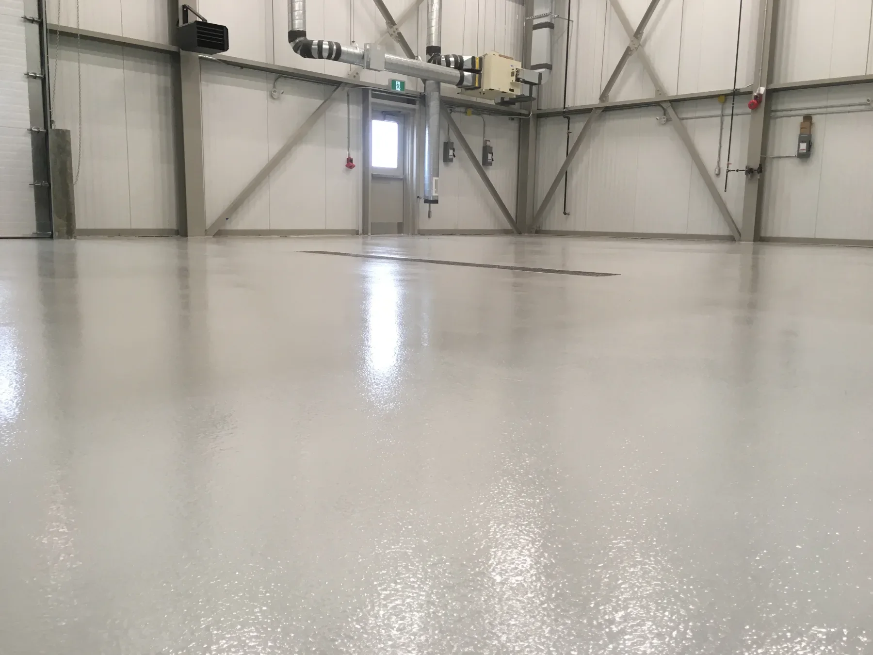 Low-angle view of a completed light-grey epoxy floor in a clean industrial facility