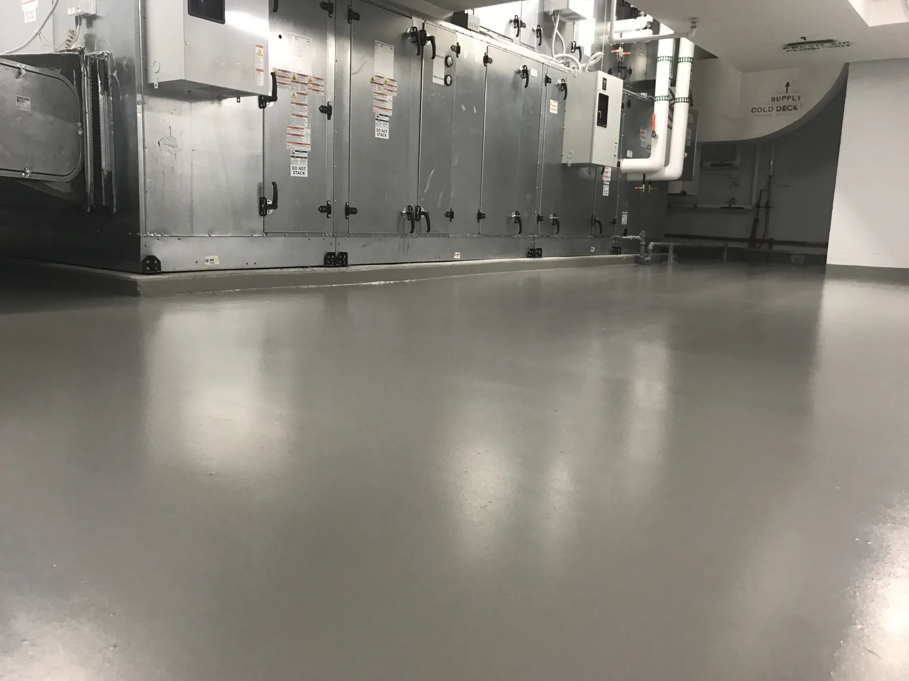 Light-grey seamless epoxy floor installed around mechanical equipment and piping