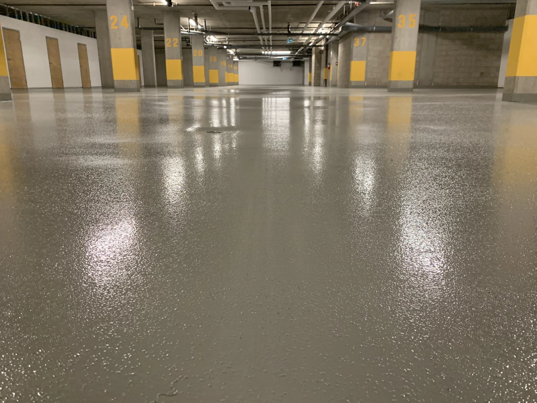 Wide view of a finished grey seamless coating in a numbered underground parking area