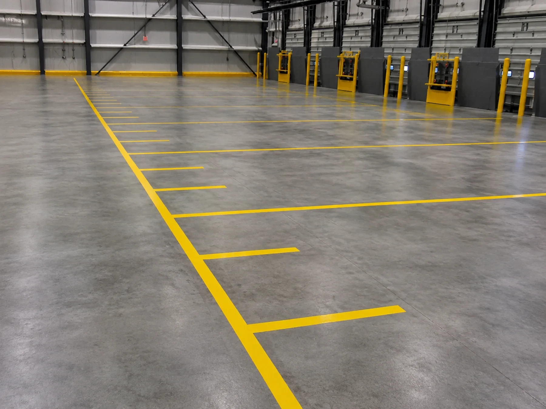 Grey industrial floor coating with bright yellow traffic and loading-bay markings