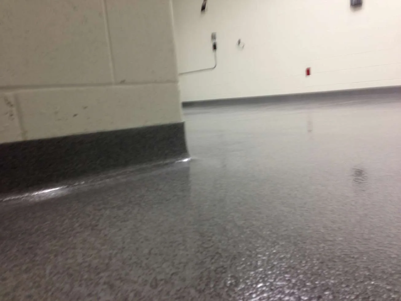 Close view of grey decorative quartz flooring and a dark cove base