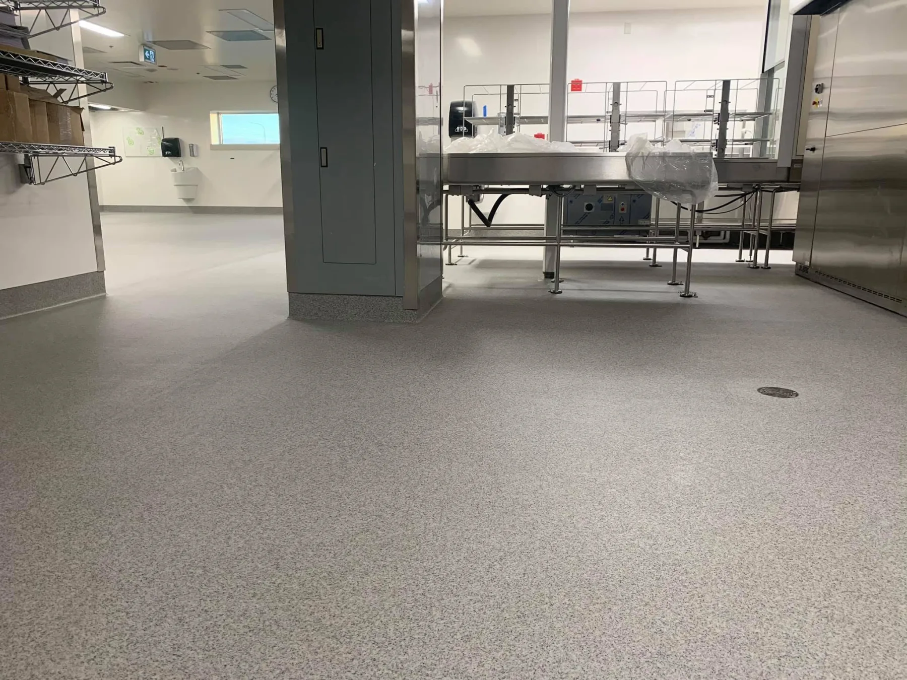 Light-grey quartz flooring surrounding stainless-steel equipment in a clean processing facility