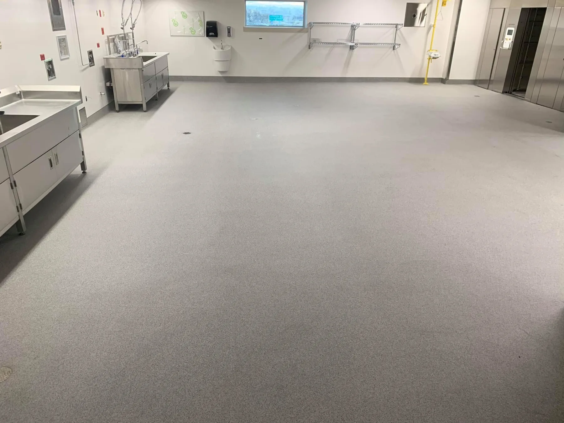 Light-grey quartz floor with drains and integral cove bases in a processing room