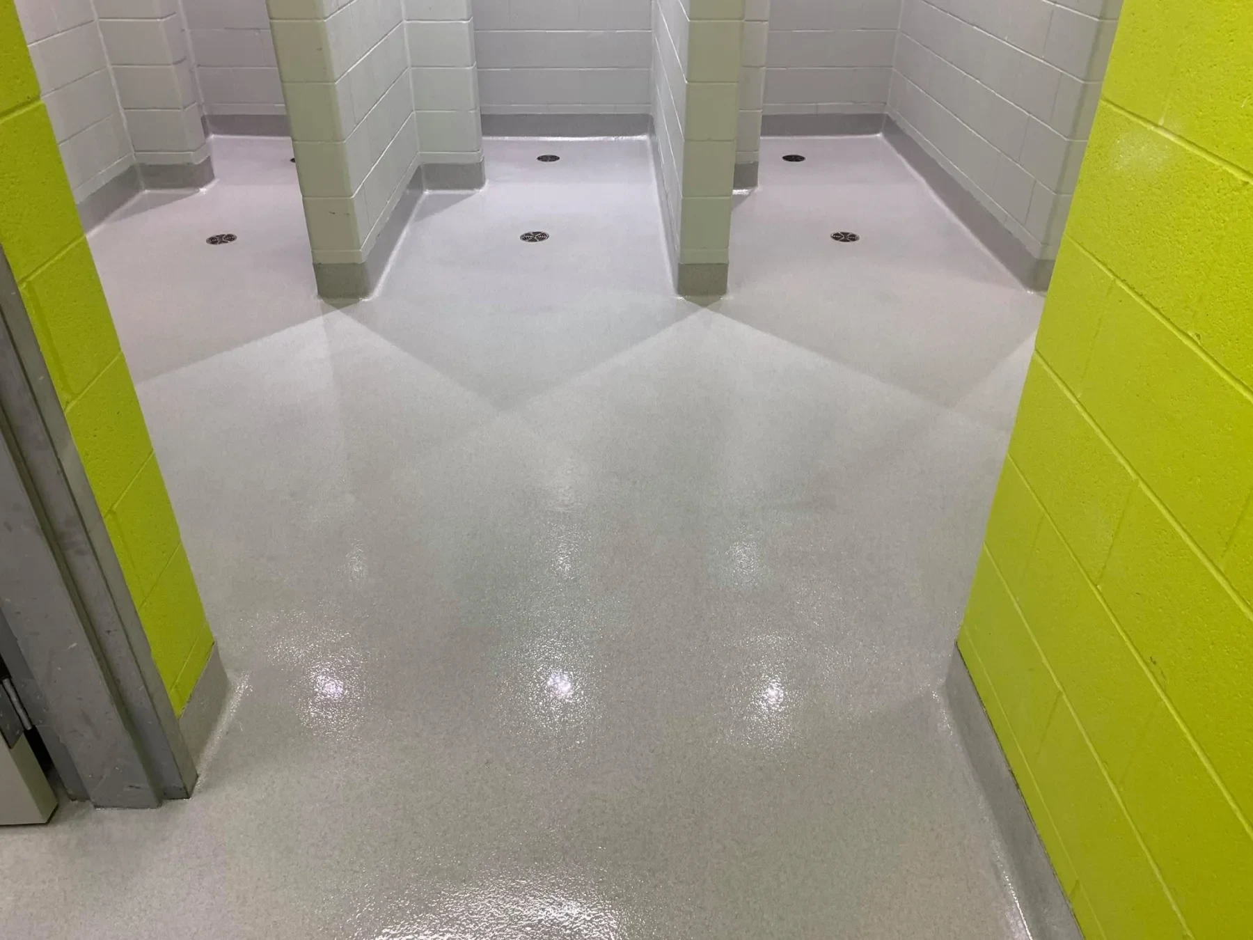 Light-grey quartz flooring with integral cove bases and floor drains in a shower area