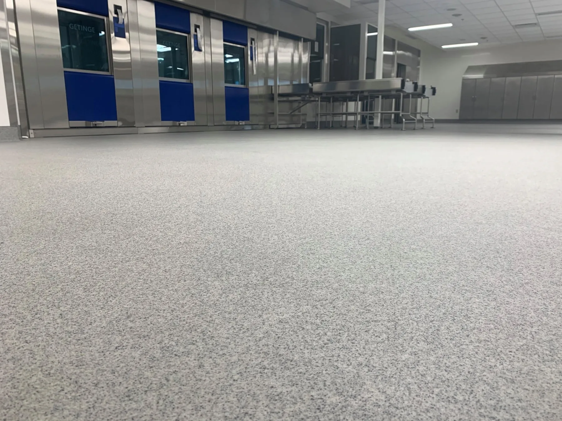 Light-grey quartz flooring in a bright room with stainless-steel sterilization equipment