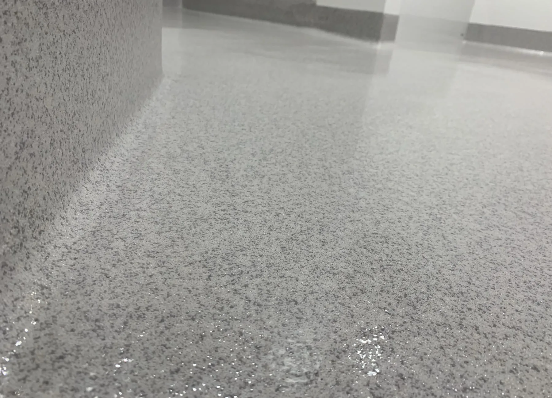 Close view of the textured surface and cove transition of a light-grey quartz floor
