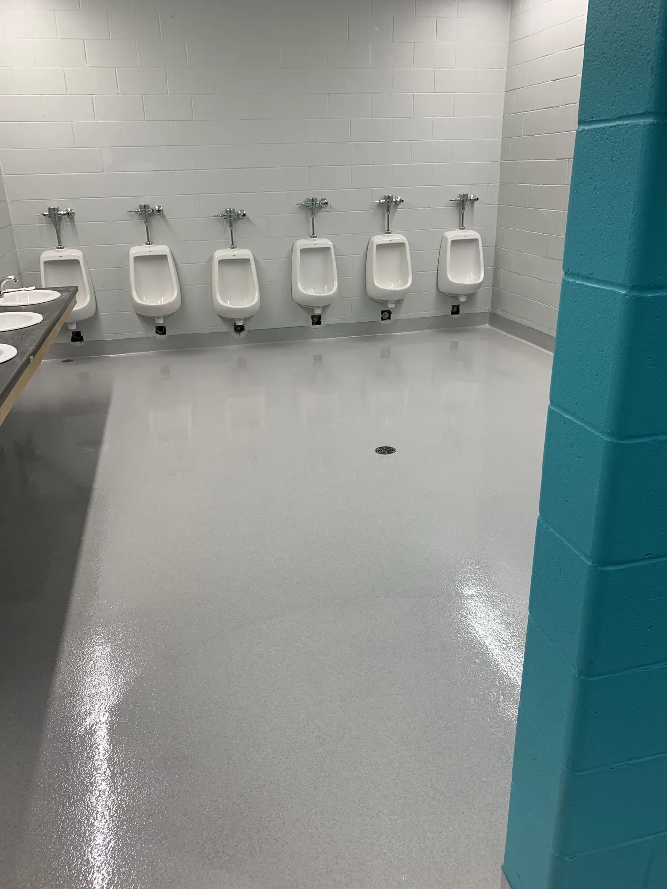 Light-grey quartz flooring with integral cove bases in a commercial washroom