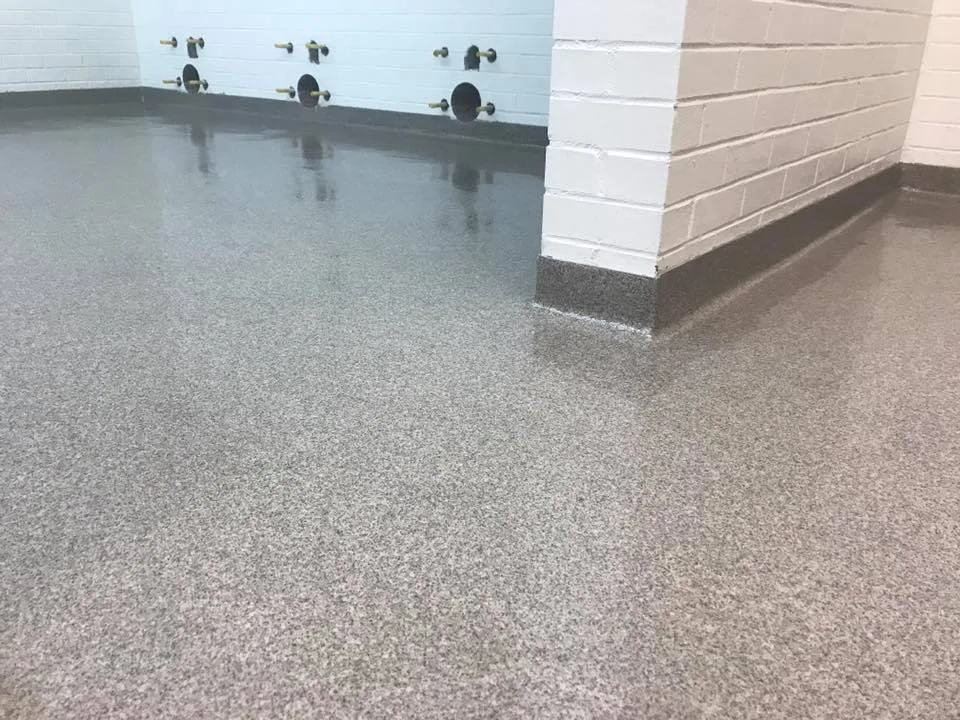 Grey troweled quartz floor beside a white masonry wall
