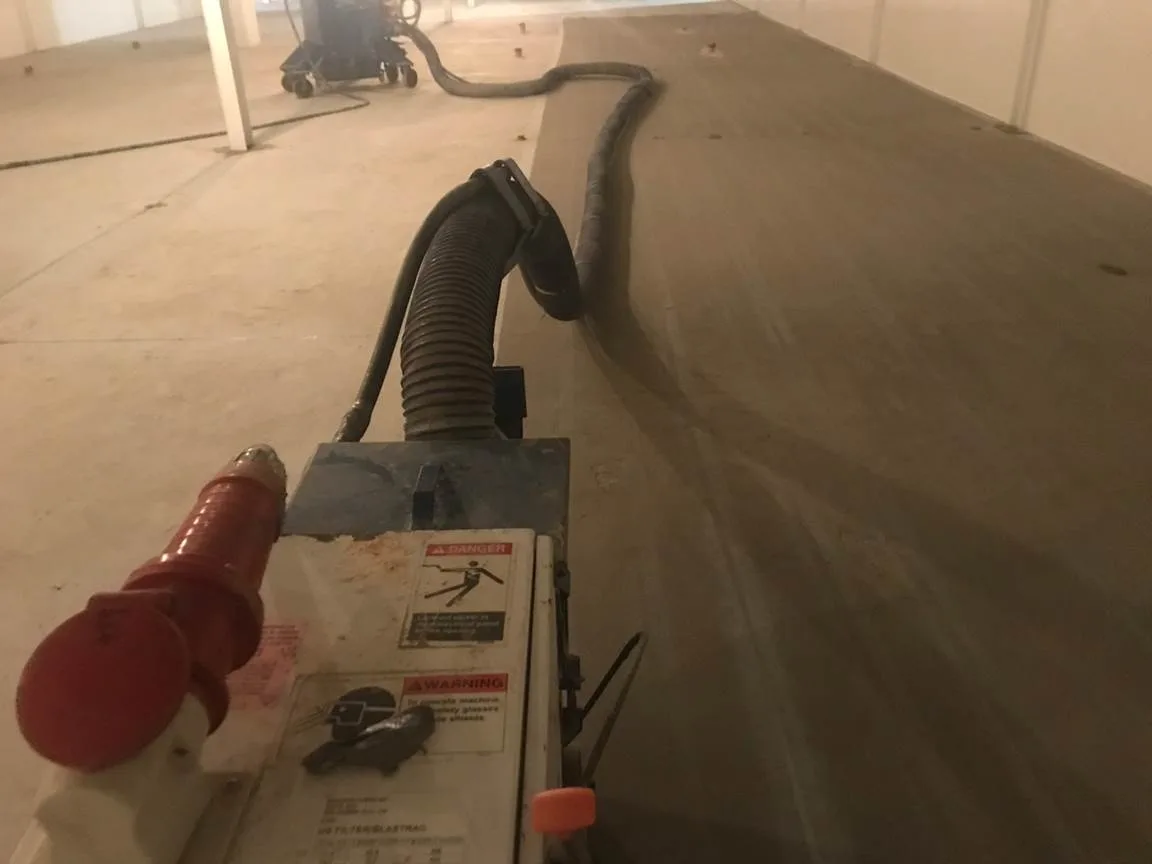 Hand grinder preparing concrete along the edge of a floor