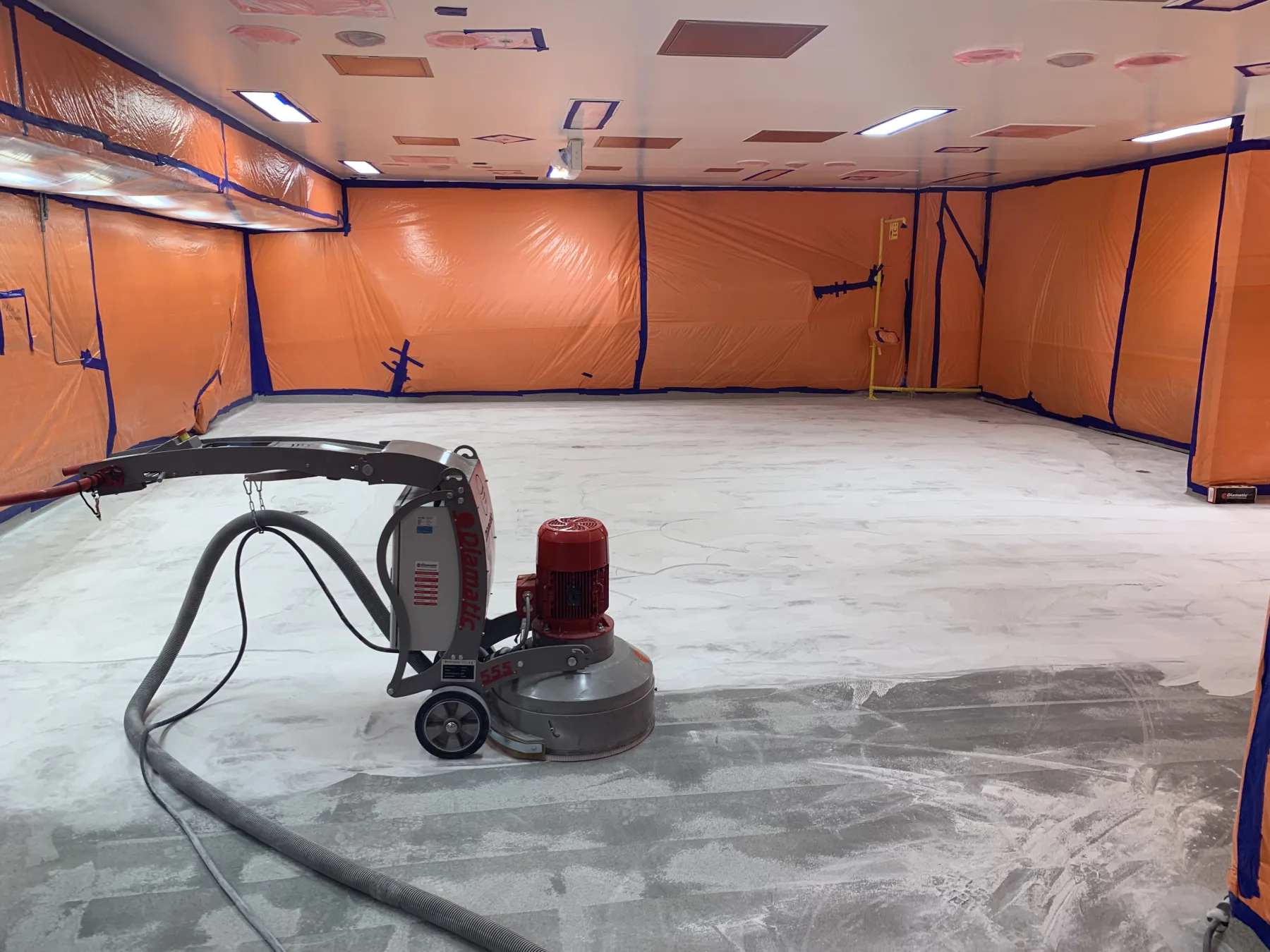 Large planetary grinder preparing a concrete floor inside a fully contained work area