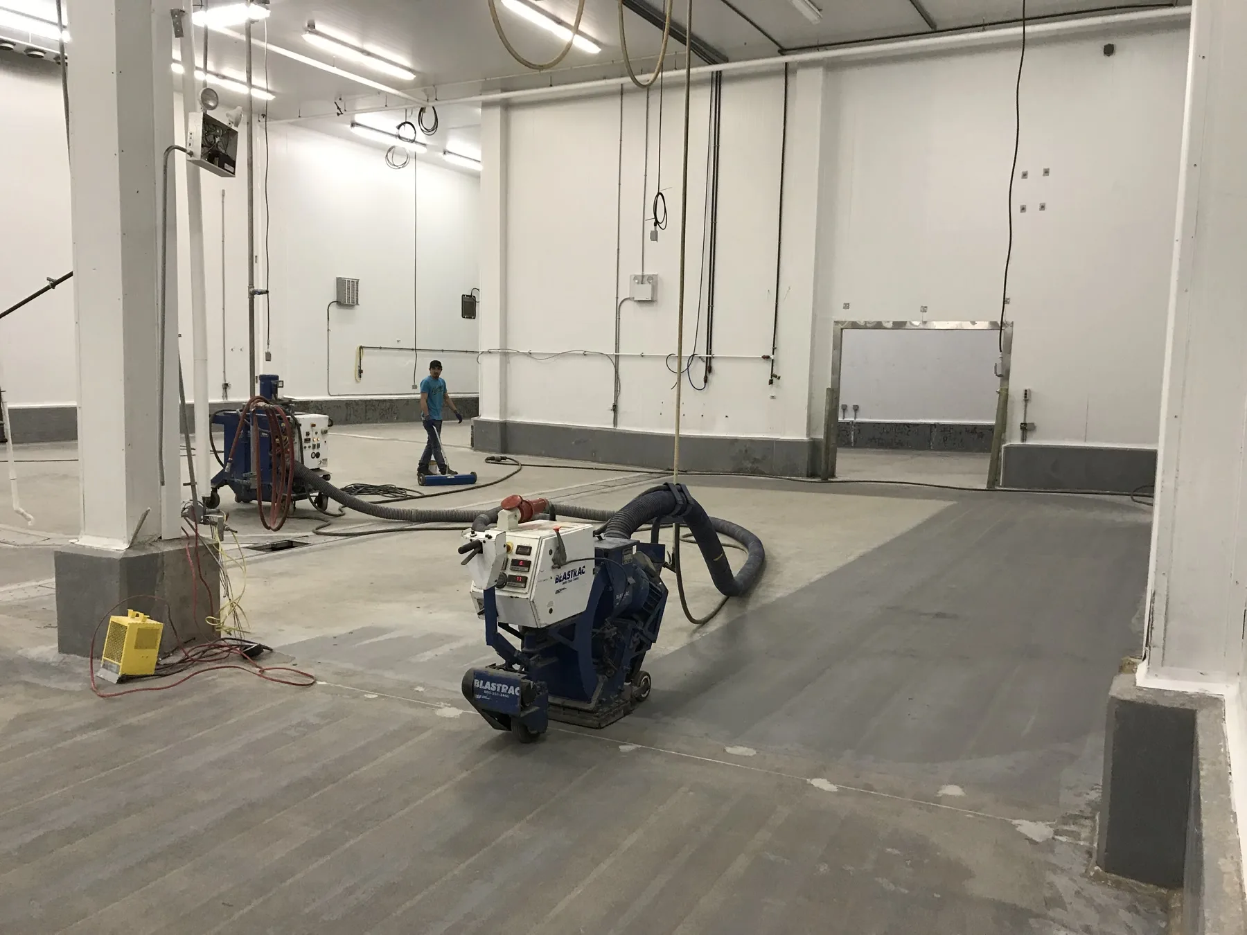 Dust-controlled shot-blasting equipment preparing an industrial concrete floor