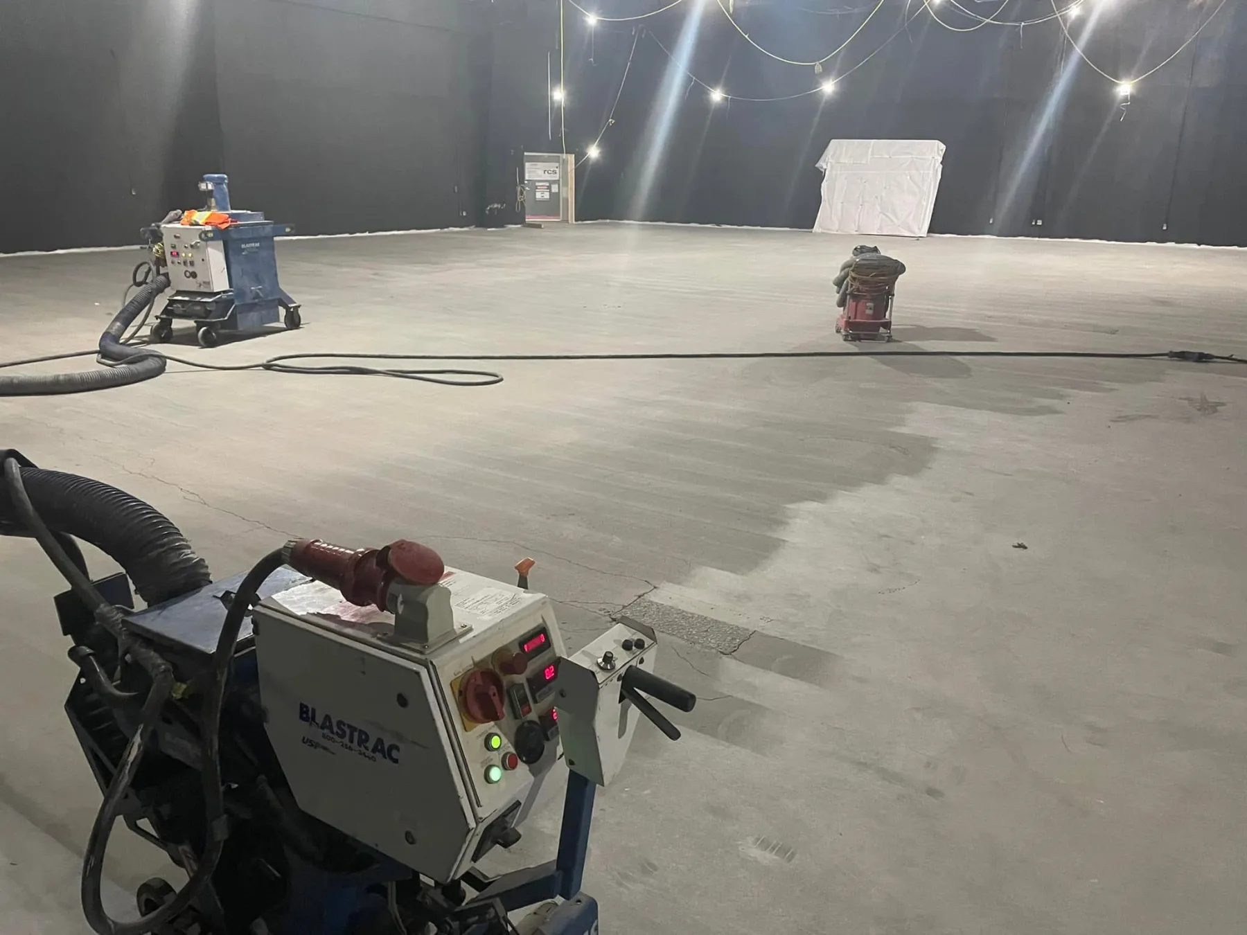 Shot-blasting and dust-control equipment mechanically preparing a large interior concrete floor