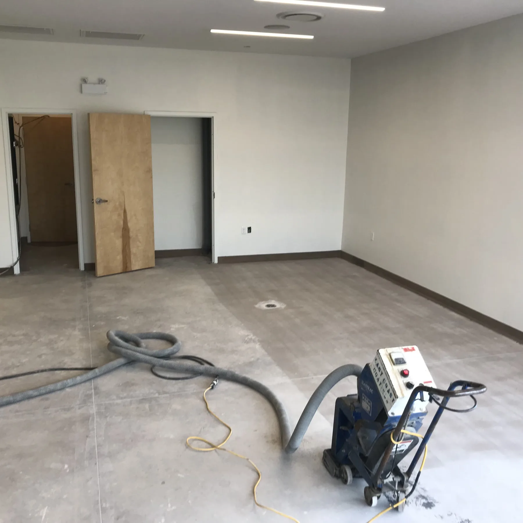 Shot-blasting equipment preparing a concrete floor in a finished interior room
